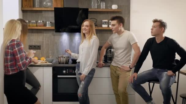 Dos chicos y tres chicas teniendo una pequeña fiesta en casa, cocinando la cena juntos . — Vídeo de stock