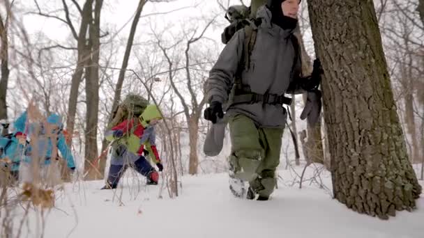 Young sportsmen hikers are walking in winter day in forest, stepping over snowdrifts, sport orienteering — Stockvideo