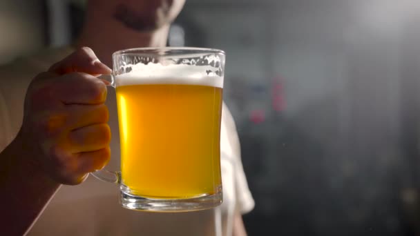 Volwassen man houdt gevuld bier mok in donkere kamer, dan verlagen, barman is de presentatie van nieuw bier — Stockvideo