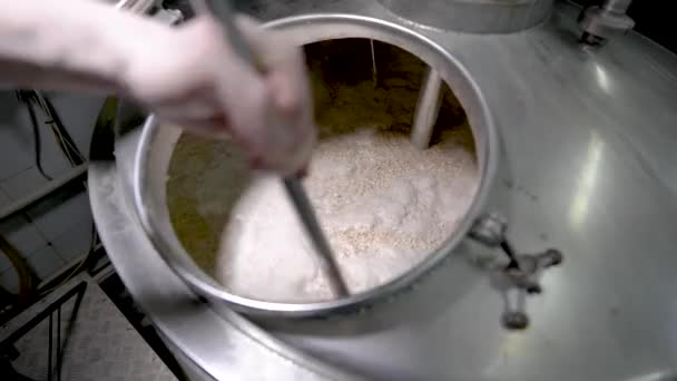 Pivovar během vaření v moderní továrně míchá slad uvnitř DPH, s podrobným výhledem, s použitím pádla
