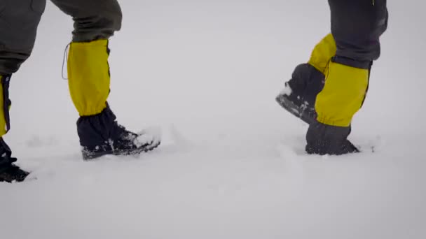 Dos hombres fueron a una expedición. Botas de trekking profesionales y polainas ayudan a moverse en la nieve — Vídeo de stock