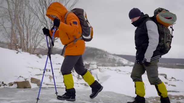 Dois homens foram fazer uma caminhada de inverno. Os amigos têm equipamento profissional, eles caminham ao longo do penhasco . — Vídeo de Stock