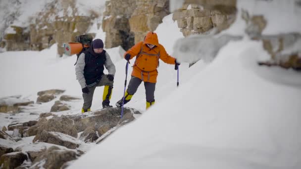 Two men went on a winter hike. Friends have professional equipment, they walk along the cliff. — Stock Video