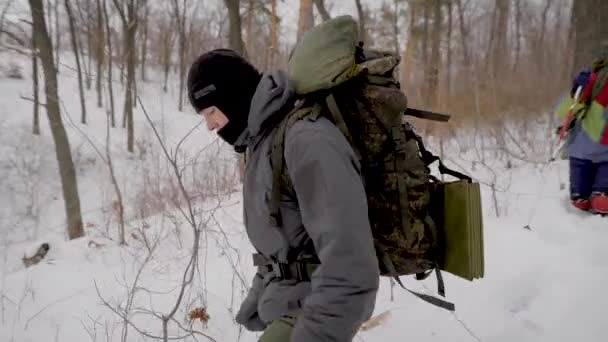 Δύο άνδρες και δύο γυναίκες πεζοπόροι περπατούν στο χειμερινό δάσος τη μέρα, βοηθώντας τους εαυτούς τους με ραβδιά — Αρχείο Βίντεο