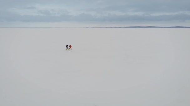 两个人在大自然中徒步旅行的鸟瞰图。冰冻的河流覆盖着厚厚的雪层. — 图库视频影像