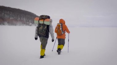 Kışın yürüyüş eken iki aktif adamın arkasından vurulmuş. Büyük çantaile donmuş göl crossing.