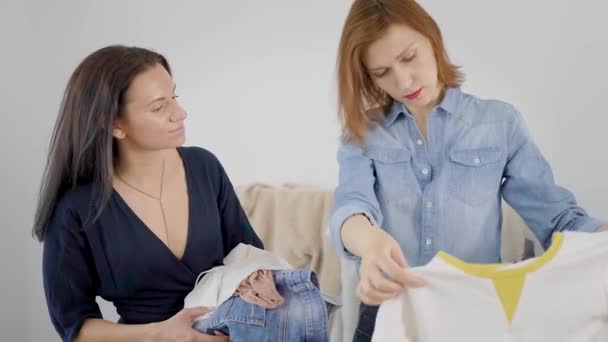 Twee vrouwen vriendin demonteren garderobe. Meisjes proberen op verschillende kleding en beslissen hoe om te kleden. — Stockvideo