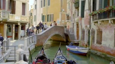 Güzel Venedik şehir manzarası. Şehirde yürüyen insanlar ve sokağın yanında park etmiş iki gondollar..