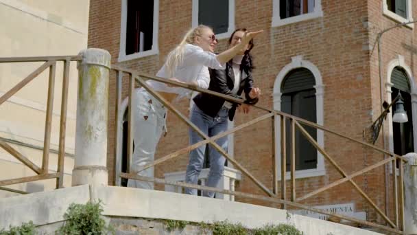 Две молодые европейки наслаждаются видом на город с балкона и разговаривают . — стоковое видео