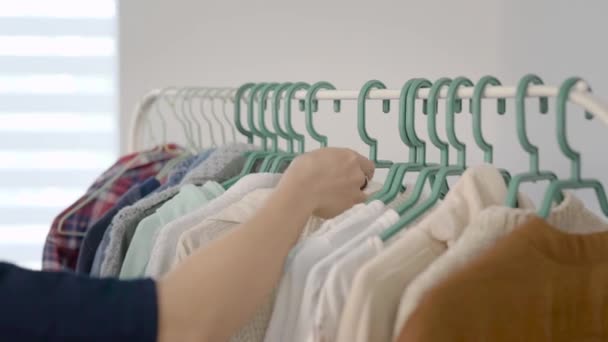 Close-up shot of a woman hand going through light tonned clothes on the rack at home. — Stock Video