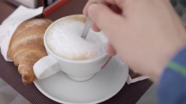 Sabah kahvaltısı, kruvasan ve cappuccino. Açık kafe verandasında kahve.
