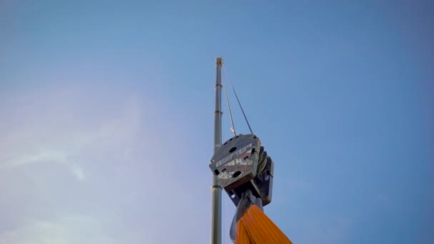 Im Rahmen befindet sich ein riesiger Kranhaken. Baustelle, Kran auf riesigen Bändern zieht die Last. — Stockvideo