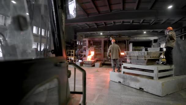 Escena sobre la producción metalúrgica. En la sombría tienda, los trabajadores supervisan el funcionamiento del horno. El horno a una temperatura enorme, derrite el metal . — Vídeo de stock