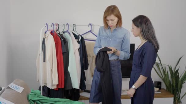 Zwei schöne junge Frauen sind mit der Analyse der Garderobe beschäftigt. Freundinnen wählen Outfits aus und holen Bilder ab. — Stockvideo