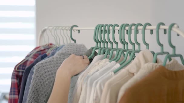 As mulheres estudam roupas penduradas num cabide. Escolher um guarda-roupa é muito importante para as mulheres modernas — Vídeo de Stock