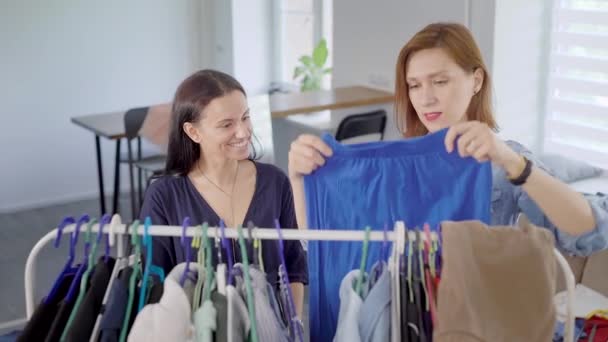Kvinnor studerar kläder hängde på en hängare. Att välja en garderob är mycket viktigt för moderna kvinnor — Stockvideo