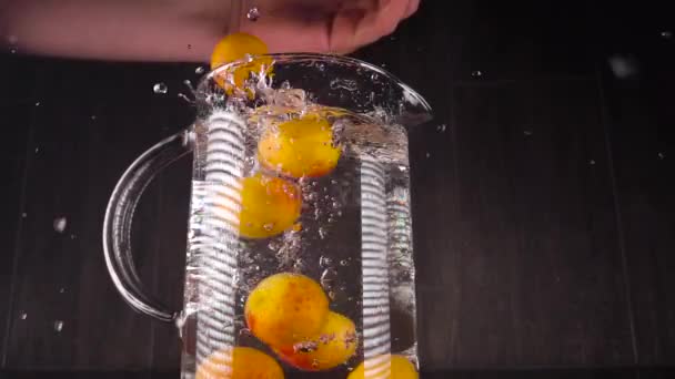 Spetteren van fruit op water. Abrikozen in slow motion vallen in een vat met water. Spectaculair frame met fruit — Stockvideo