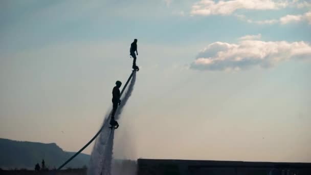 A légbeszálló. Két sportolók repülnek a flyboards a víz felett. A férfiak különböző trükköket és fordulatok. Extrém vízisport. — Stock videók