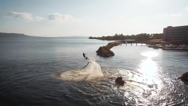 Flyboarden, een nieuw extreem soort activiteit. een slimme atleet voert verschillende trucs uit over water. Flips, U-bochten en bochten. Extreme levensstijl en wateractiviteit — Stockvideo