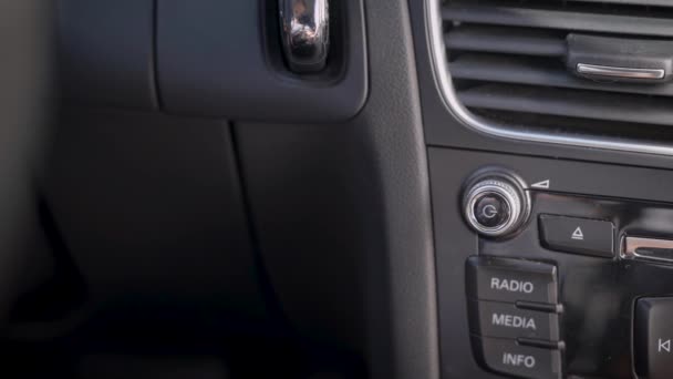 Na moldura, a mão de um homem e um botão de volume de áudio do carro. O condutor ou passageiro ajusta o nível de volume da música . — Vídeo de Stock
