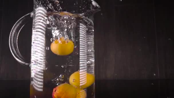 Salpicando fruta en el agua. Los albaricoques en cámara lenta caen en un recipiente con agua. Marco espectacular con frutas — Vídeos de Stock