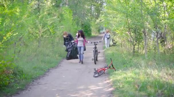 A group of women and children collect garbage in the forest. Volunteers collect plastic and other waste in black plastic bags. People are responsible for the environment. — Stock Video