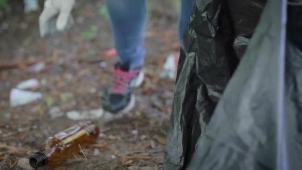 Der unkenntliche Mensch sammelt Müll, der auf der Natur liegt. Leider liegt jetzt viel Müll und Umweltverschmutzung im Wald, auf der Promenade und in der Natur. — Stockvideo