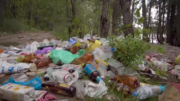 Un gran vertedero ilegal en un sendero forestal. Un montón de plástico, bolsas, botellas y otros residuos contamina el medio ambiente. No es un hermoso paisaje sucio, una triste vista . — Vídeos de Stock