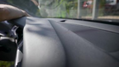 Bir adam bir arabayı peçeteyle ovuyor. Premium otomobilin iç panellerinin bakımı ve temizliği yapılmaktadır. Arabanın iç kaliteli malzemelerden yapılmıştır.