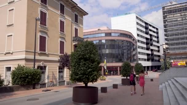 Switzerland, cityscape of Lugano. A pair of young people are walking around the city, Girl in red, Man in black. — Stock Video