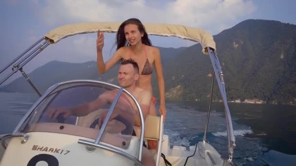 Um homem e uma mulher montam um barco a motor num belo lago. Um casal amoroso passa suas férias fazendo esportes ativos. Lago Lugano — Vídeo de Stock