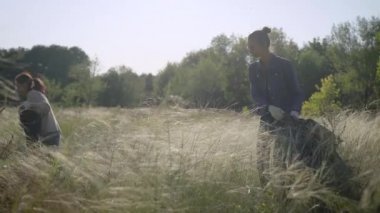 Eldivenli ve siyah plastik çöp torbalı iki kız tarlada yürüyor. Gönüllüler doğada mevcut çöp toplamak.