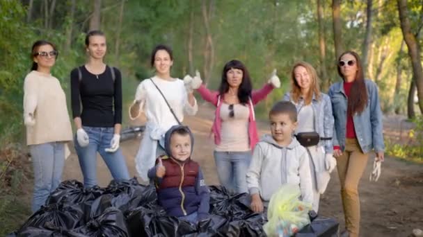 Een groep jonge vrouwen en kinderen verzamelde veel vuilniszakken in de natuur. Vrijwilligers zijn blij met het resultaat, het park werd schoongemaakt van vervuiling, een milieu campagne werd gehouden. — Stockvideo