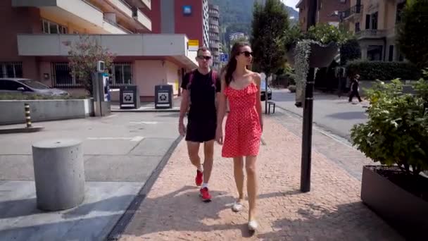 Marito e moglie viaggiano in estate in Europa. Abbigliamento in stile leggero e casual. Bella coppia di giovani, una donna in rosso, un uomo in nero . — Video Stock