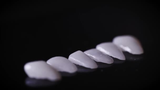 Un macroscatto di faccette dentali. Le faccette sono speciali cuscinetti per denti che svolgono una funzione estetica. La moderna produzione di precisione consente di creare il sorriso perfetto . — Video Stock