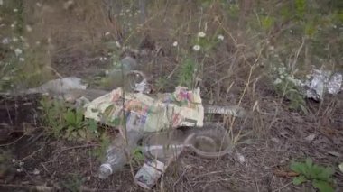 Doğada çöp. Gazete, plastik şişeler ve diğer çöpler çevreyi kirletmektedir..