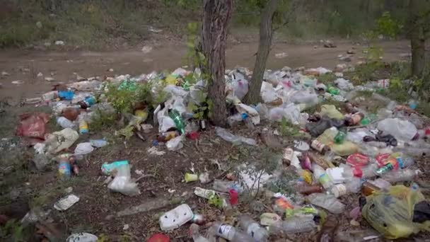 Un gran vertedero ilegal en un sendero forestal. Un montón de plástico, bolsas, botellas y otros residuos contamina el medio ambiente. No es un hermoso paisaje sucio, una triste vista . — Vídeos de Stock