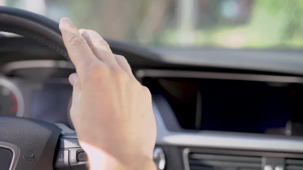 Мужчина кладет руку на руль автомобиля, сидя внутри, крупным планом в машине в дневное время — стоковое видео