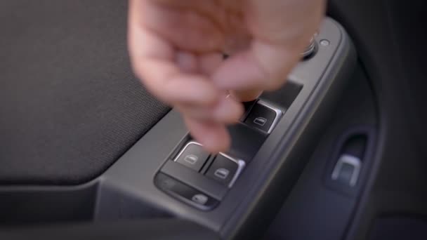 Οδηγός πιέζει τα κουμπιά των διακοπτών παραθύρων με τηλεχειριστήριο στο εσωτερικό του σύγχρονου αυτοκινήτου, κοντινό πλάνο του χεριού — Αρχείο Βίντεο