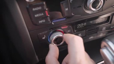 erkek sürücü otomobilde klima sıcaklığı değişiyor, kontrol paneli üzerinde döner anahtarı