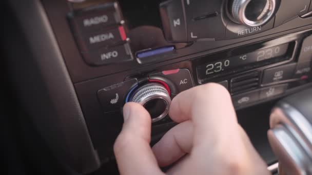 Az ember kapcsol egy klímaberendezést az autóban, és beállítja a hőmérsékletet kerek kar, közeli tekintettel a kéz — Stock videók
