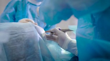 Diş hekimleri diş sağlığı kliniğinde ameliyat yapıyor. Hasta genel anestezi altında masada yatıyor.