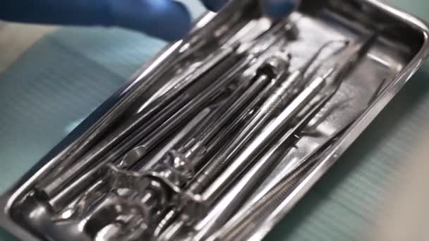 Cirujano dental está eligiendo y tomando herramienta estéril de acero de la caja de metal en el quirófano, primer plano de la mano — Vídeo de stock