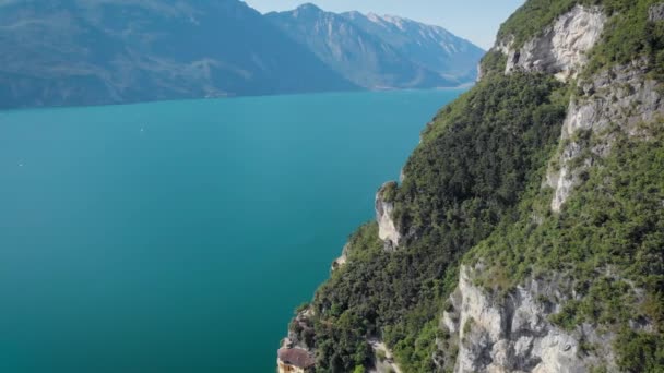 Drone está voando sobre incrível lago de montanha com água azul-turquesa, ao longo do monte alto floresta coberta em dia ensolarado — Vídeo de Stock