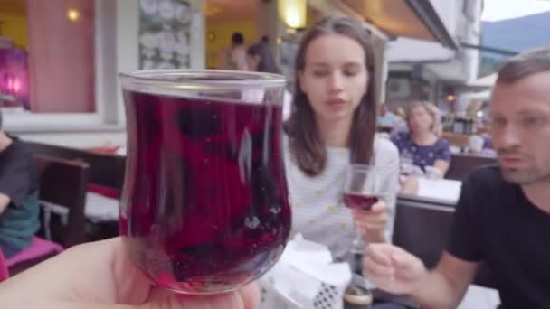 Man håller bägaren med röd saft och spottar glasögon med två hans vänner under lunchen i restaurangen — Stockvideo