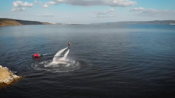 Sportman vliegt op Flyboard op het meer overdag, het uitvoeren van truc, lucht in beweging rond uitzicht — Stockvideo