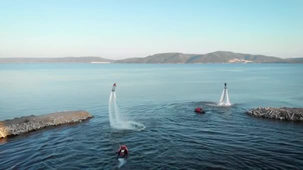 Vista aerea di formazione flyboarding team in mare, due uomini stanno volando e vorticando in aria nella giornata estiva — Video Stock