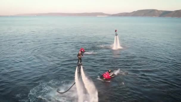 Vrolijke mannelijke flyboarder vliegt over het zeeoppervlak en poseert voor aerocamera in de lucht overdag, sportactiviteiten — Stockvideo