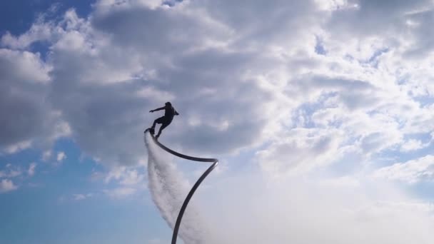 Deportista está realizando volteretas en el levantamiento de aire por flyboard sobre la superficie del lago en el día de verano — Vídeo de stock