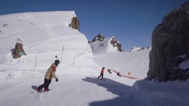 Snowboardcular güzel alp yamaçlarında gezerler. Güneşli kış günü.